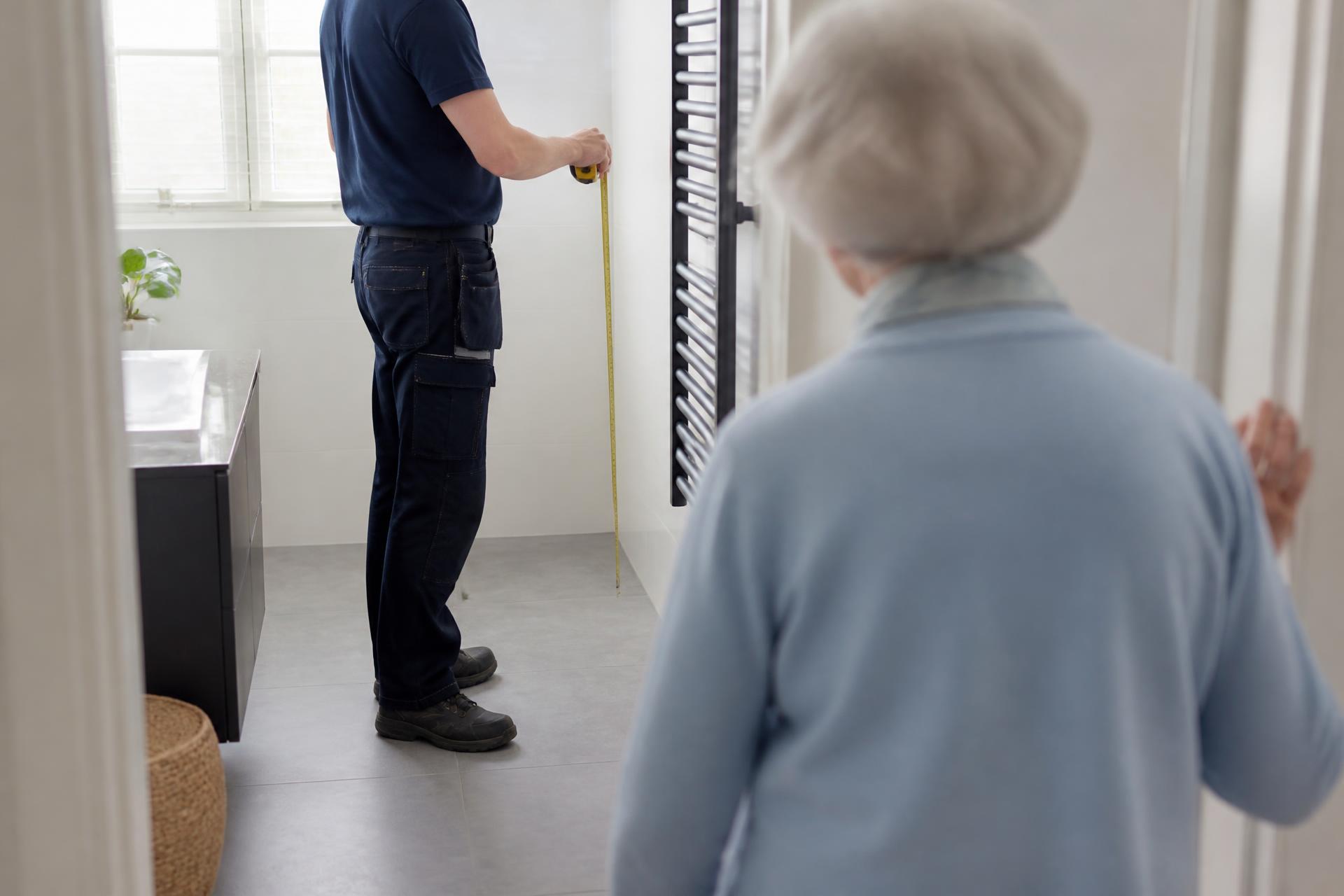 Vakman meet een badkamer op tijdens een adviesgesprek aan huis